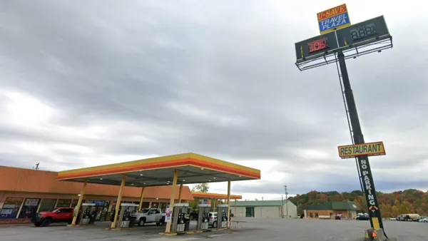 A photo of the exterior of a travel stop. A sign in the parking lot says u-save  travel plaza.