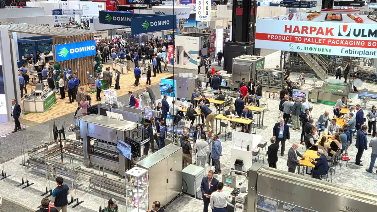 An aerial view of a trade show floor where companies display machinery and products in their booths.
