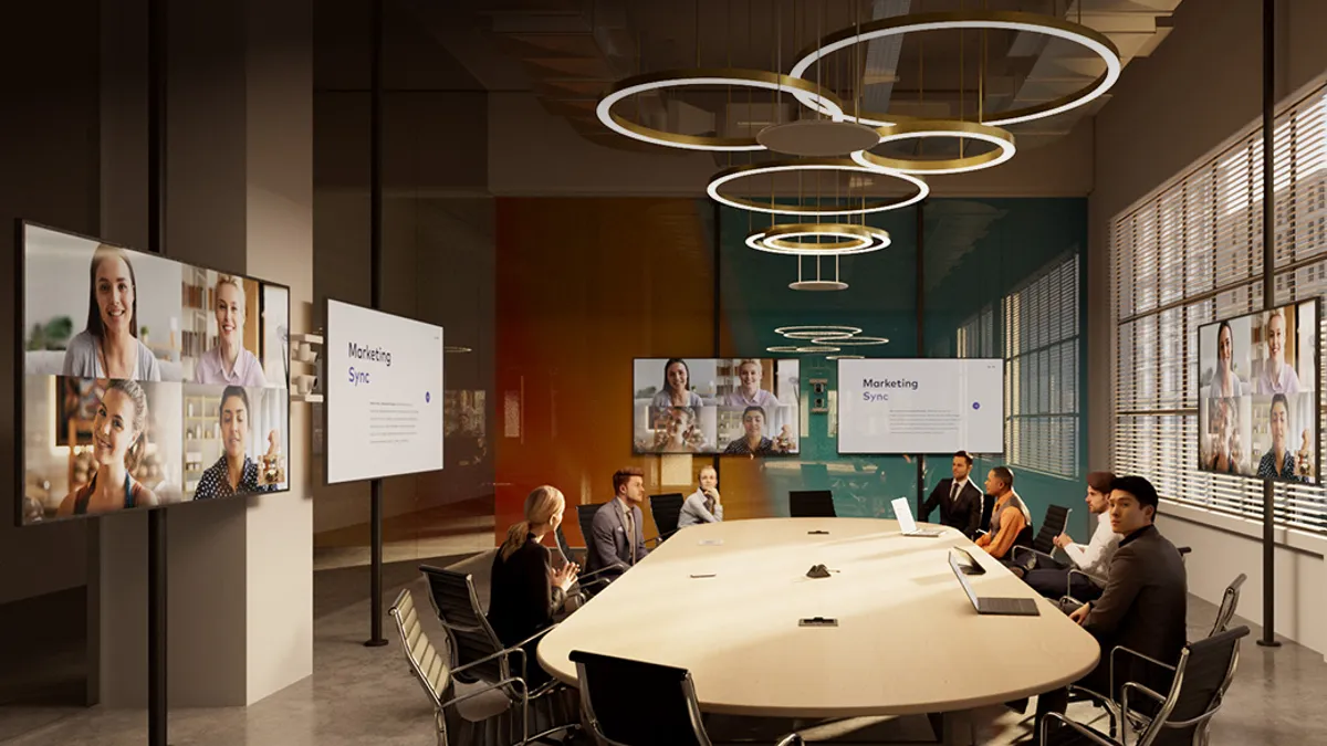 Group of people having a meeting inside a room along with video conferencing with others using digital screens.