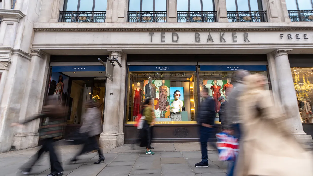 Storefront of Ted Baker with people walking down the street.