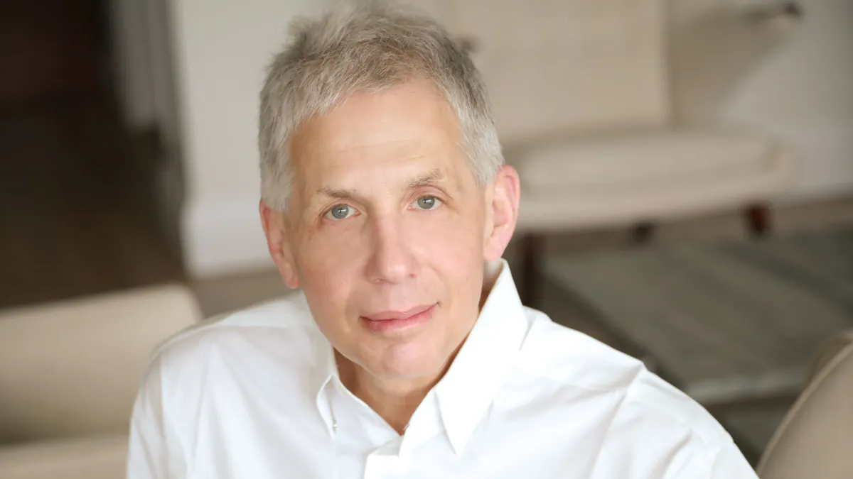 A person in a white shirt sits in an office for a photograph.