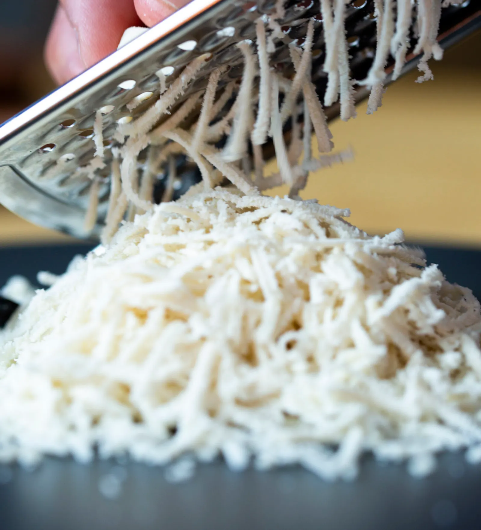 Mozzarella cheese being shredded on a grater