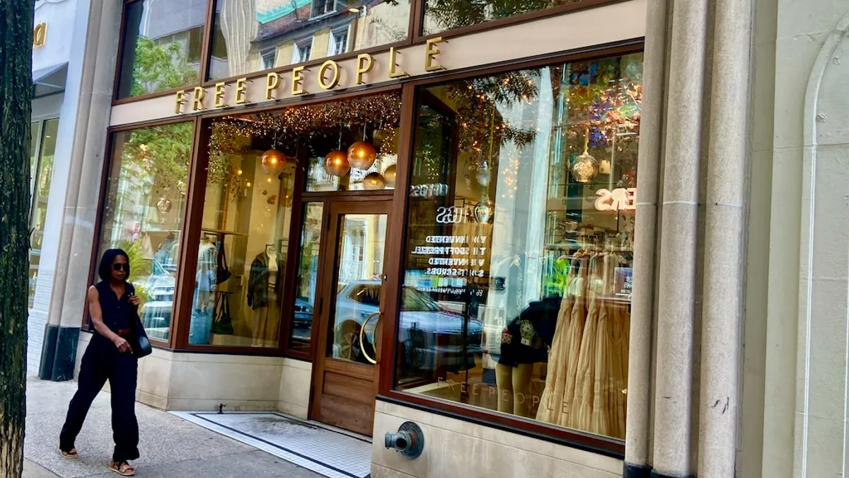 A person wearing sunglasses walks past a store.