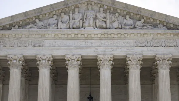 A view of the top of a building exterior that has columns and the phrase "equal justice under law" written above.