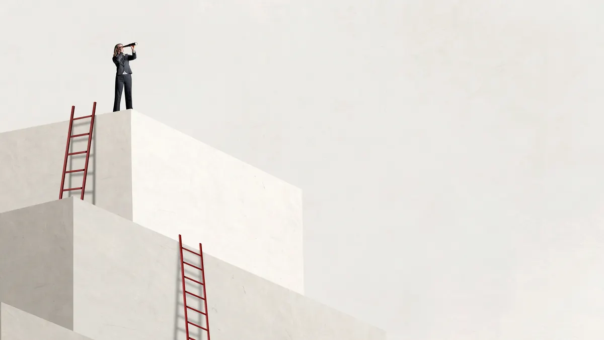 A woman who has climbed a ladder to reach the next level looks through a spyglass into the distance.