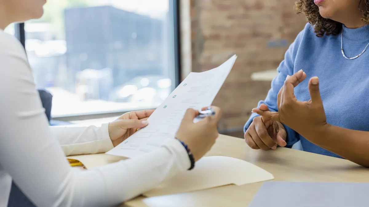 An unrecognizable woman enumerates her job experience in her interview with the female manager.