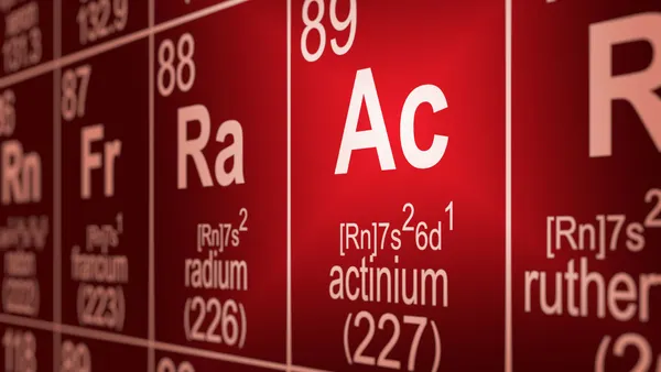 A periodic table of the elements centered on the element actinium is partially blurred.
