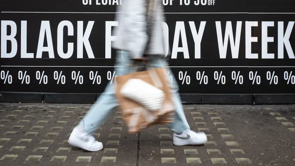 Shoppers walk through the retail district near Oxford Circus in front of a Black Friday sign.