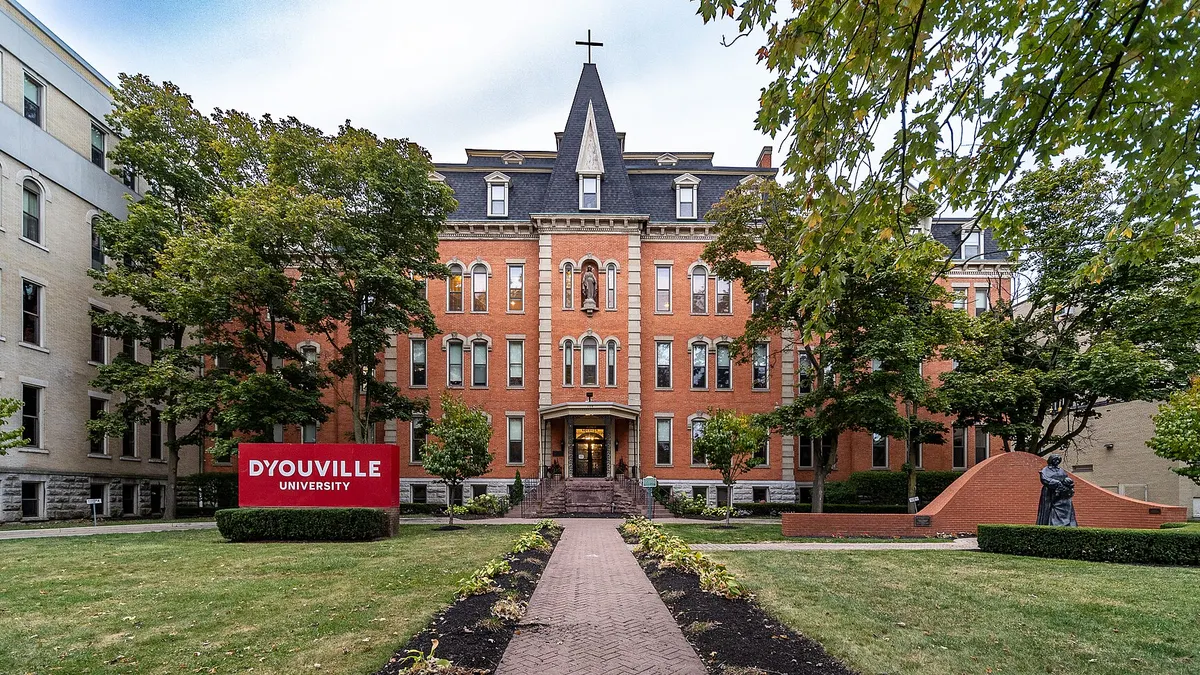 Brick building in background with university sign on quad in foreground.