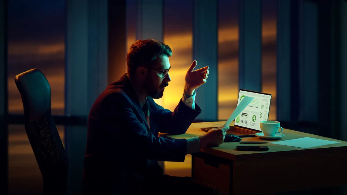 Businessman sitting in his office late, reviewing financial reports during business crisis, working on strategies.