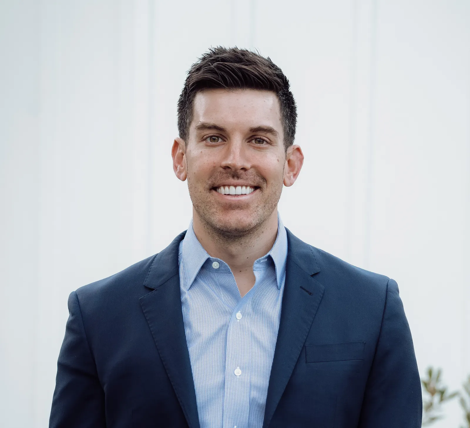 A man wearing a blue suit against a white background.