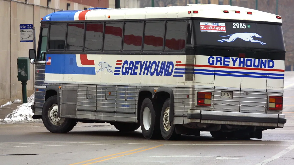 A Greyhound bus making a left turn on a Chicago street seen from the rear.