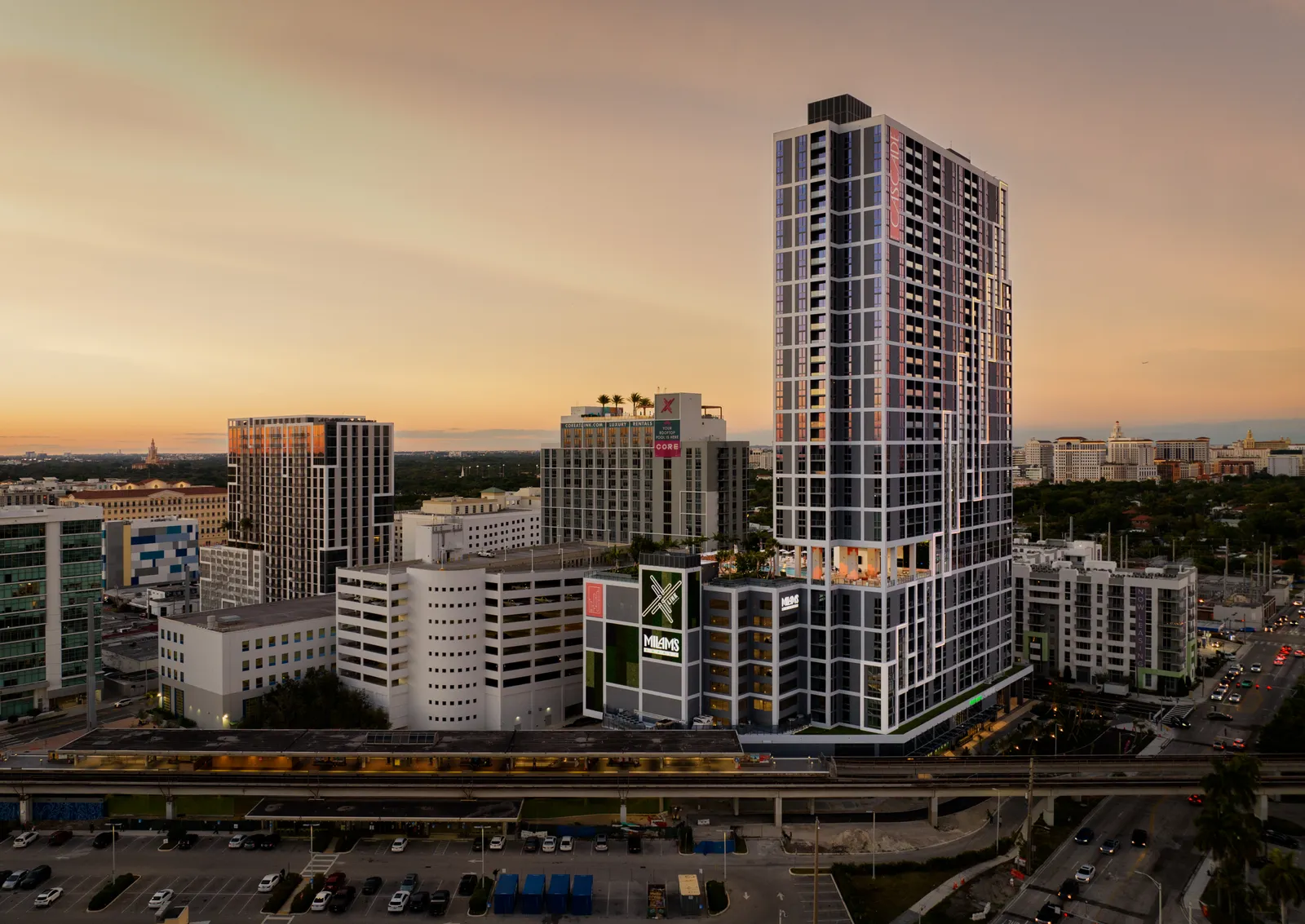 A tall, glass-and-steel apartment building at sunset.