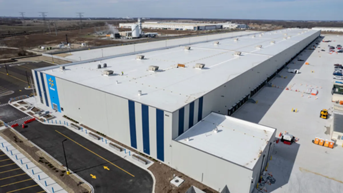 A large warehouse surrounded by a a parking lot and trucking lot.