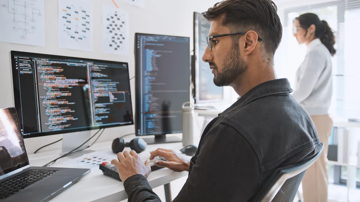 a software developer types at his desk, using an external monitor