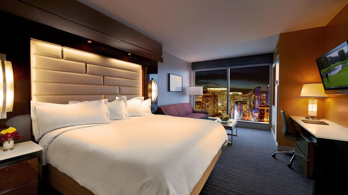 A bedroom with a view of the Las Vegas skyline at night.