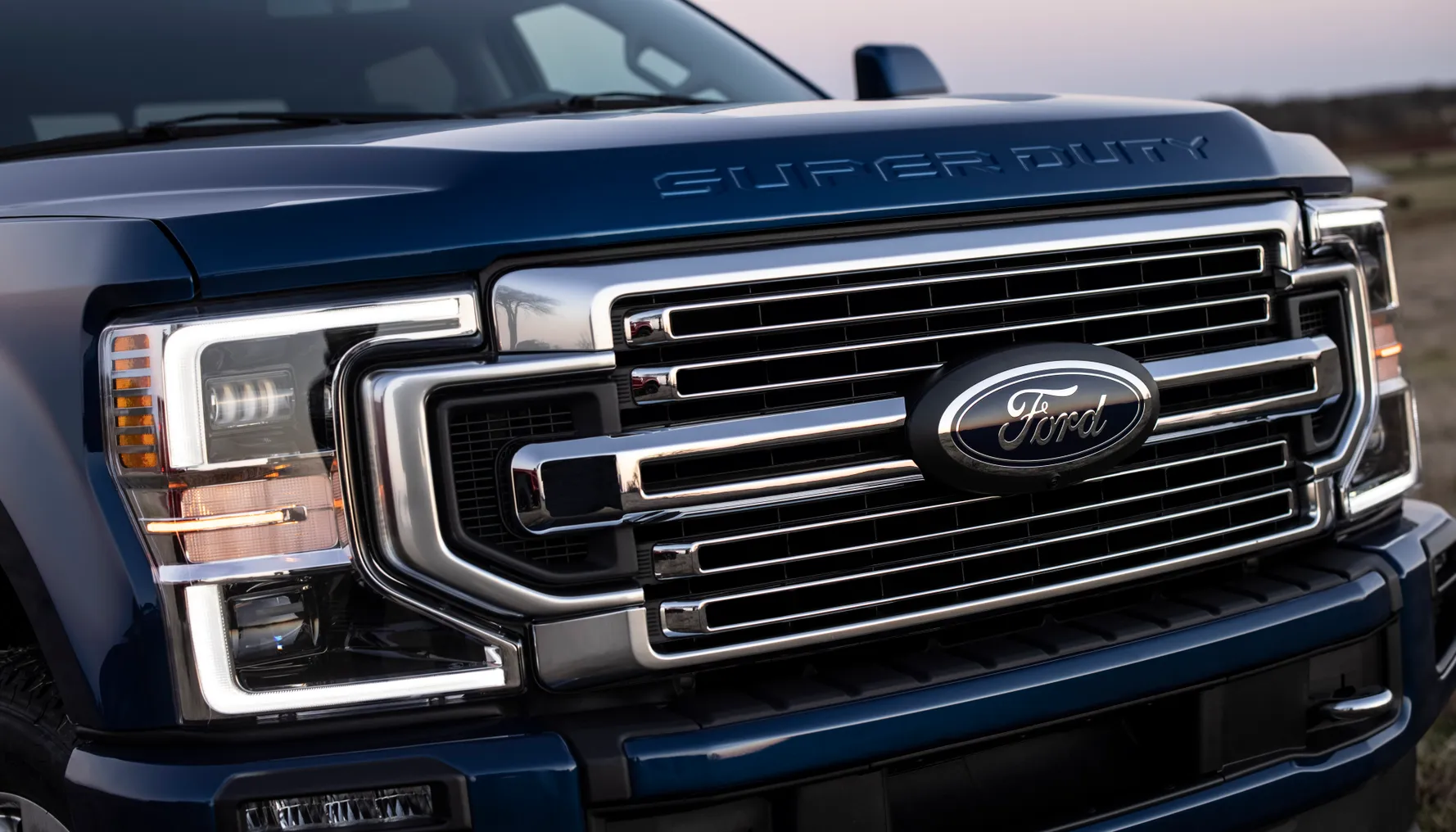 The front grill showing a Ford badge on a dark blue 2022 Ford F- Series Super Duty pickup truck.