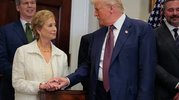 Education Secretary Linda McMahon and President Donald Trump clasp hands as they speak to each other