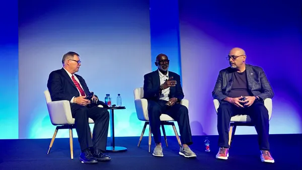 Three tech executives sit on a stage during a panel interview