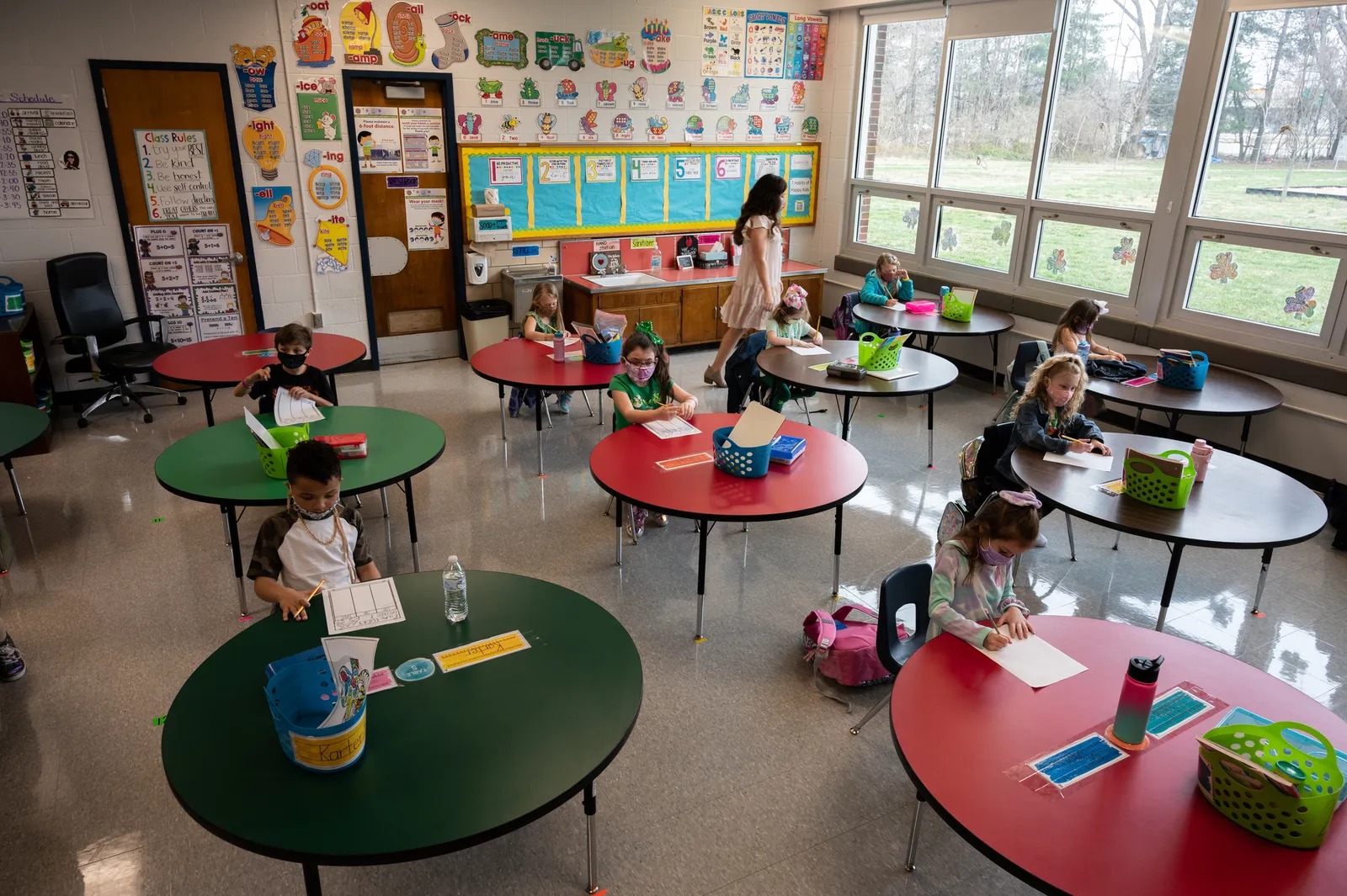 A teacher walks among masked students sitting in a socially distanced classroom  at Medora Elementary School on March 17, 2021 in Louisville, Kentucky.