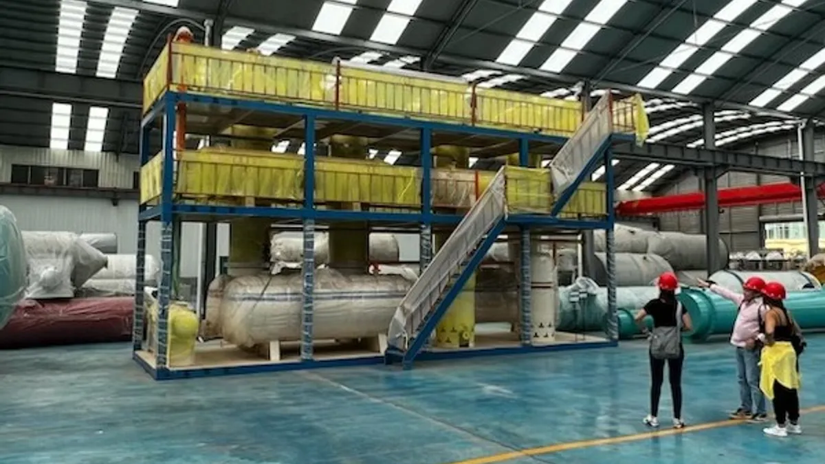 People standing next to equipment in a manufacturing facility.