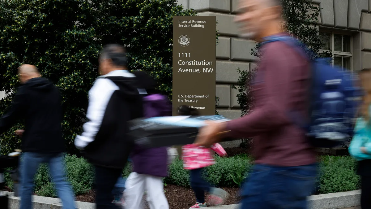 People walk past a sign for the Internal Revenue Service.