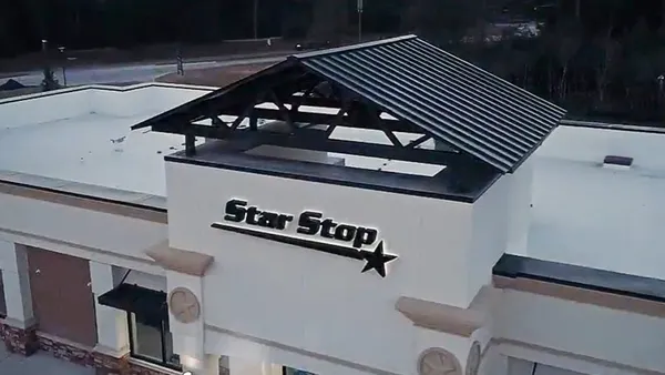 A photo of the outside of a building. A sign on the gray wall says Star Stop.