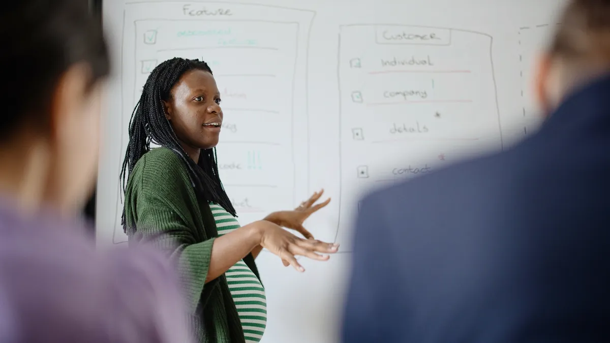 A pregnant worker gives a presentation at the office.