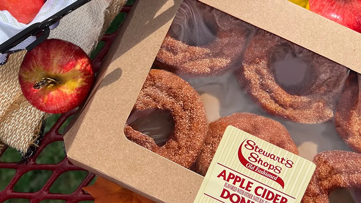 A photo of cider donuts from Stewart's Shops surrounded by fall items like apples and orange maple leaves.