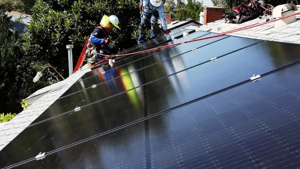 Two men install solar panels on a rooftop.