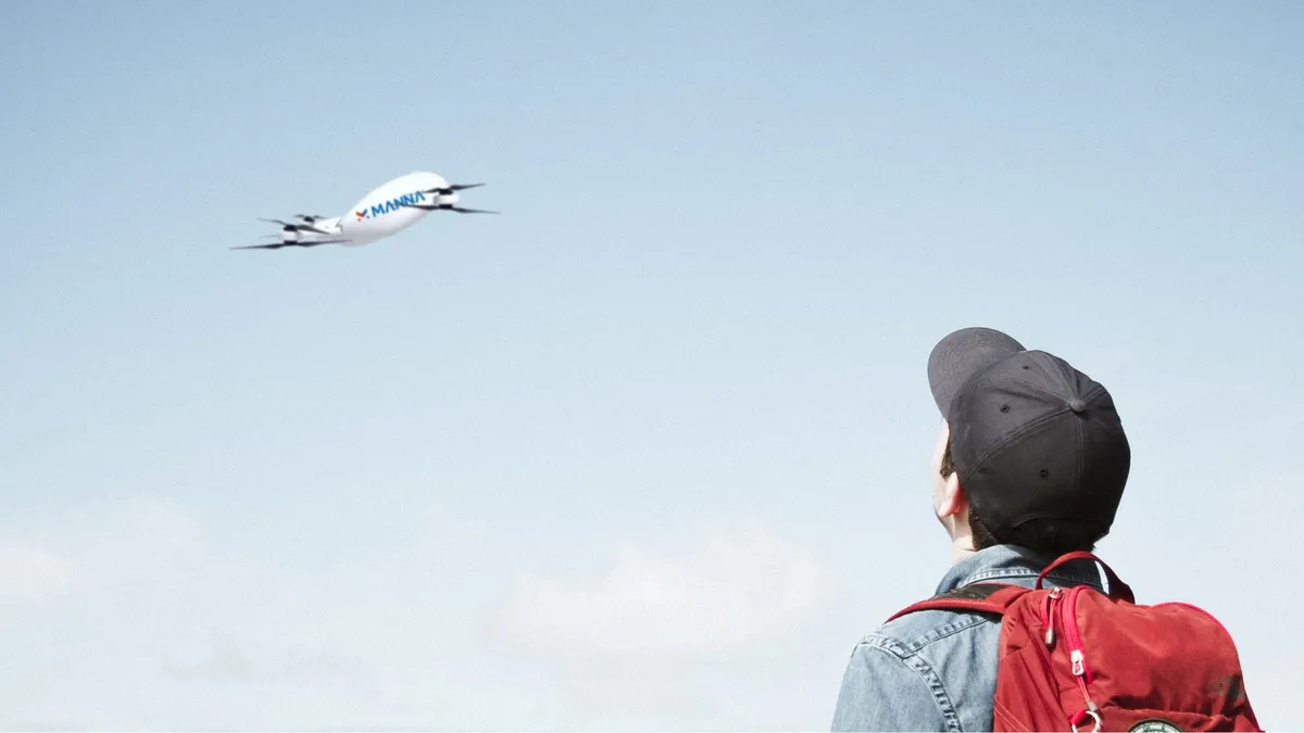 Bystander looks up at a Manna delivery drone up in the sky