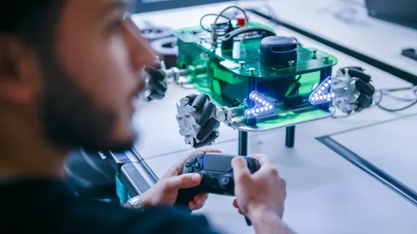 A man uses a controller to operate an artificial intelligence system on the table in front of him.