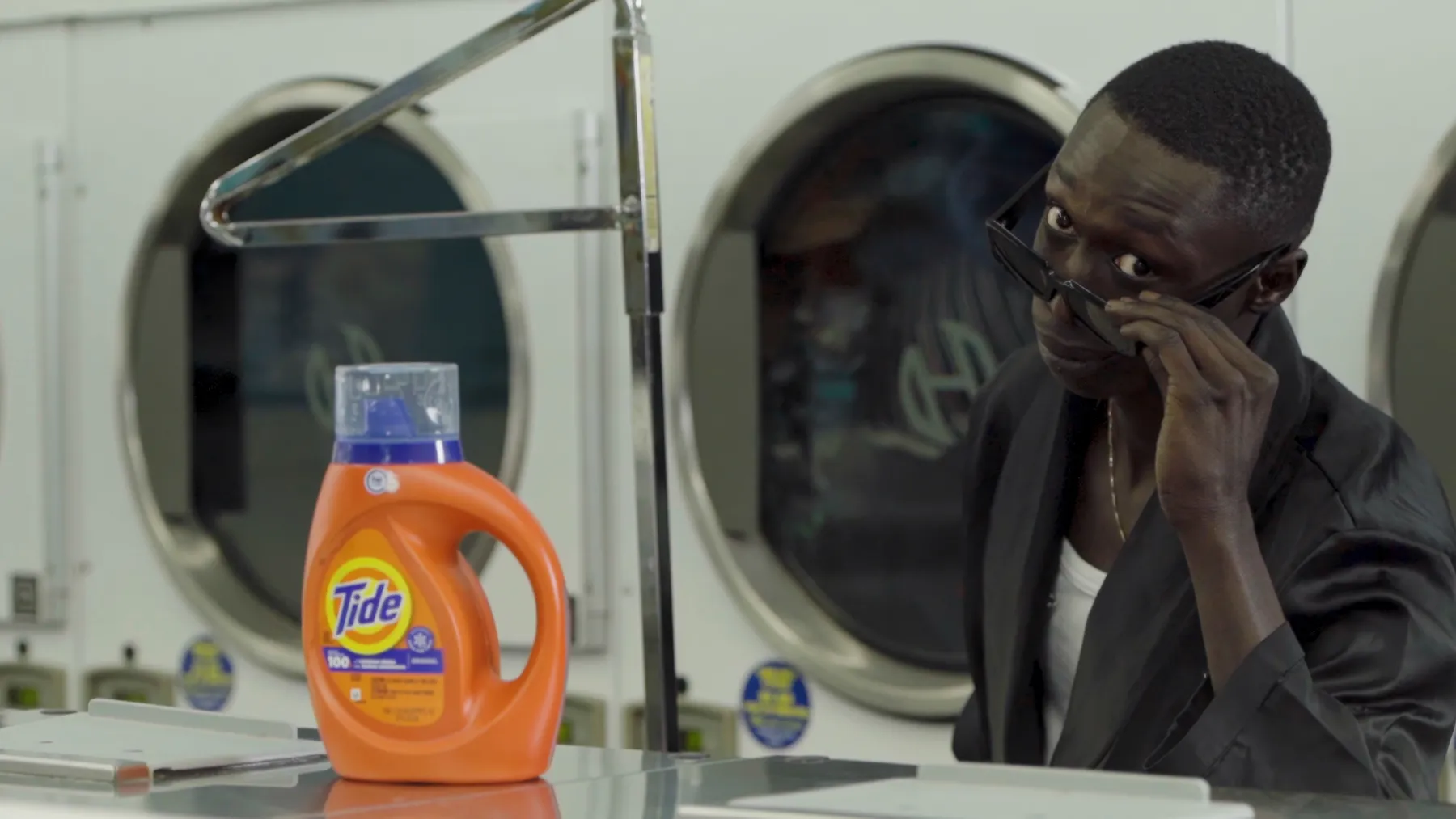 Khaby Lame with a bottle of Tide in a laundromat