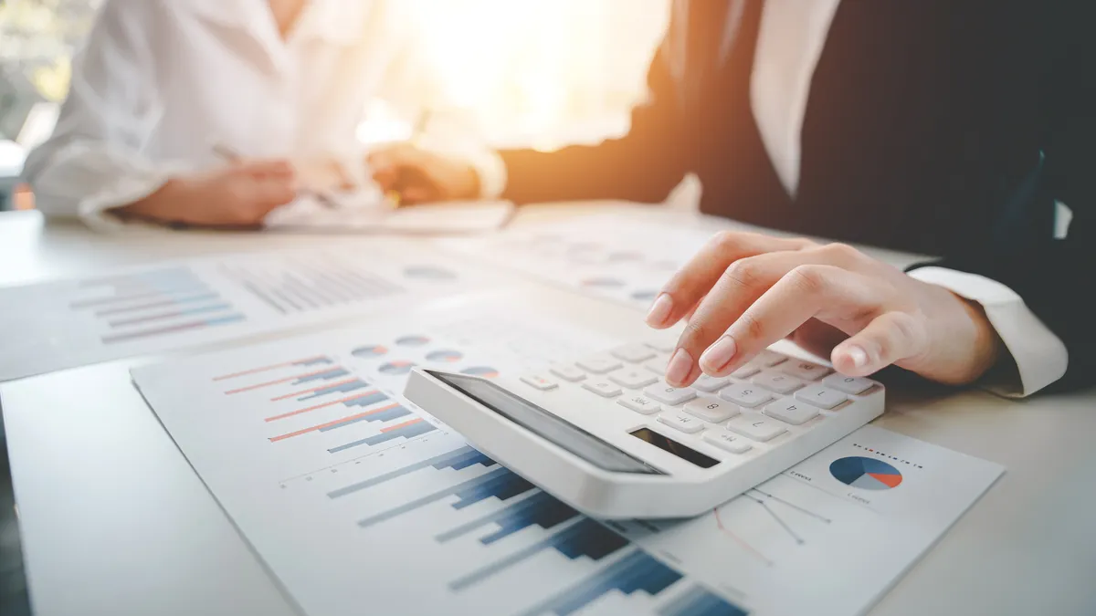 Two people sitting at a table with financial documents and a calculator