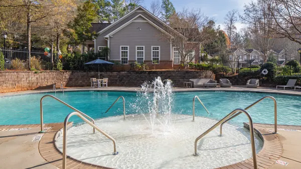 A pool with garden-style apartments in the background
