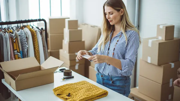 Female owener of small business packing product in boxes, preparing it for delivery