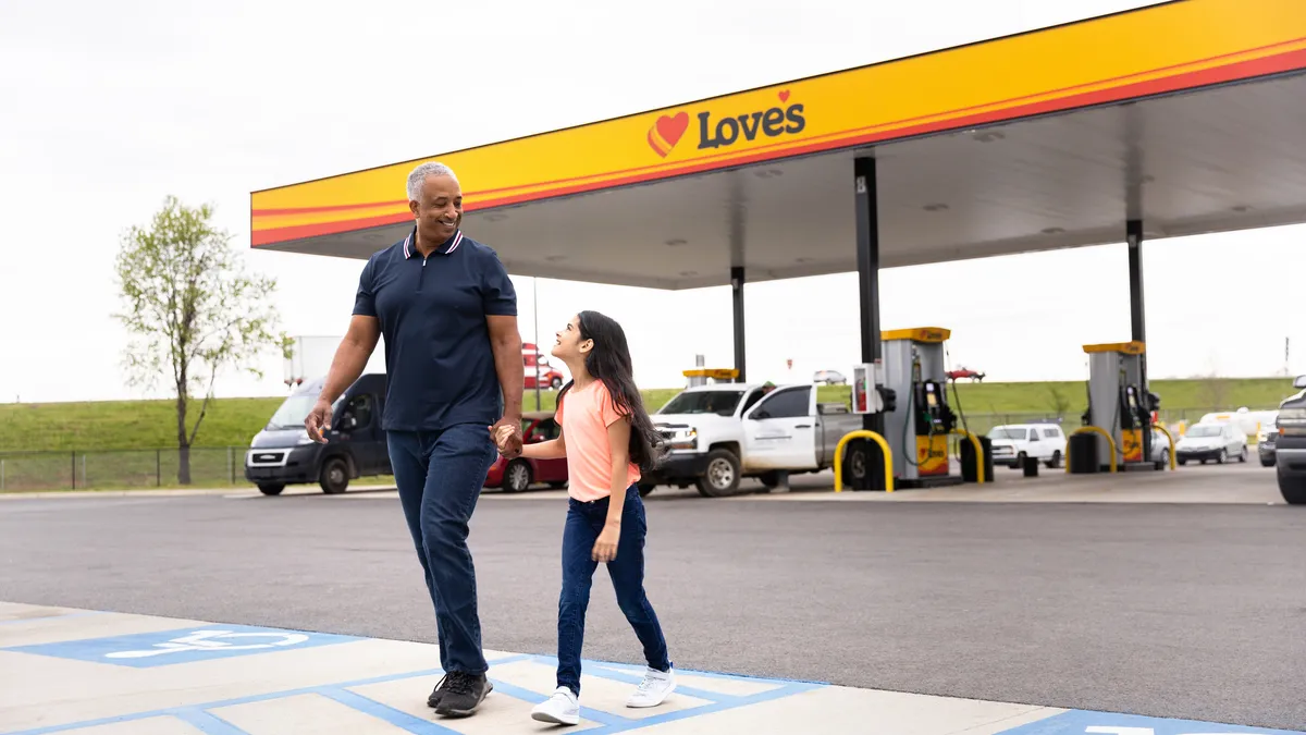 A photo of an adult and a child walking and holding hands in front of a Love's