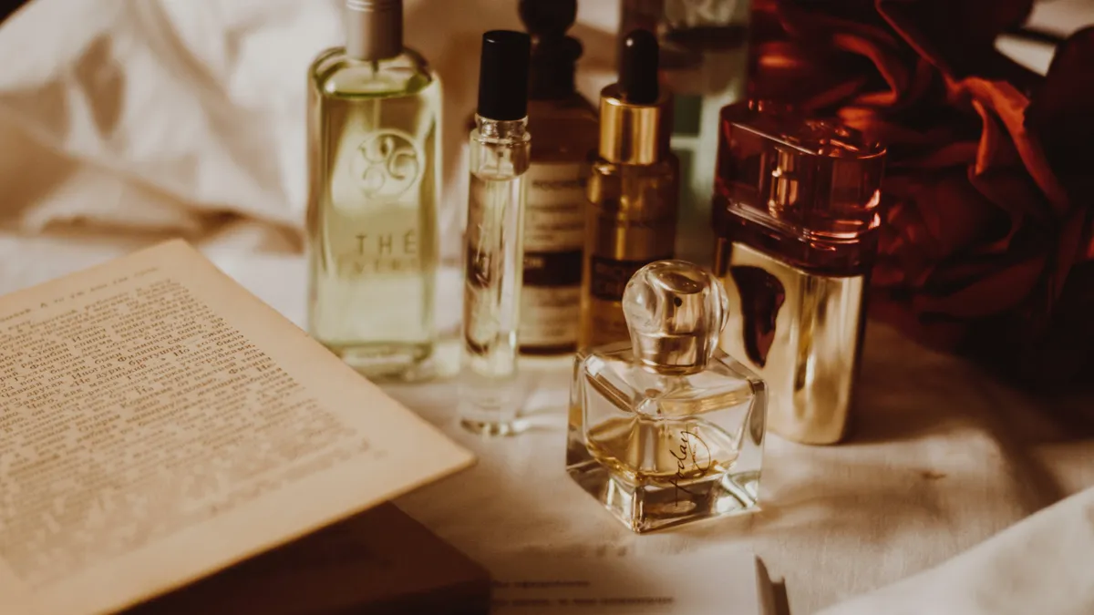 Perfume bottles sit on a desk with an open book.