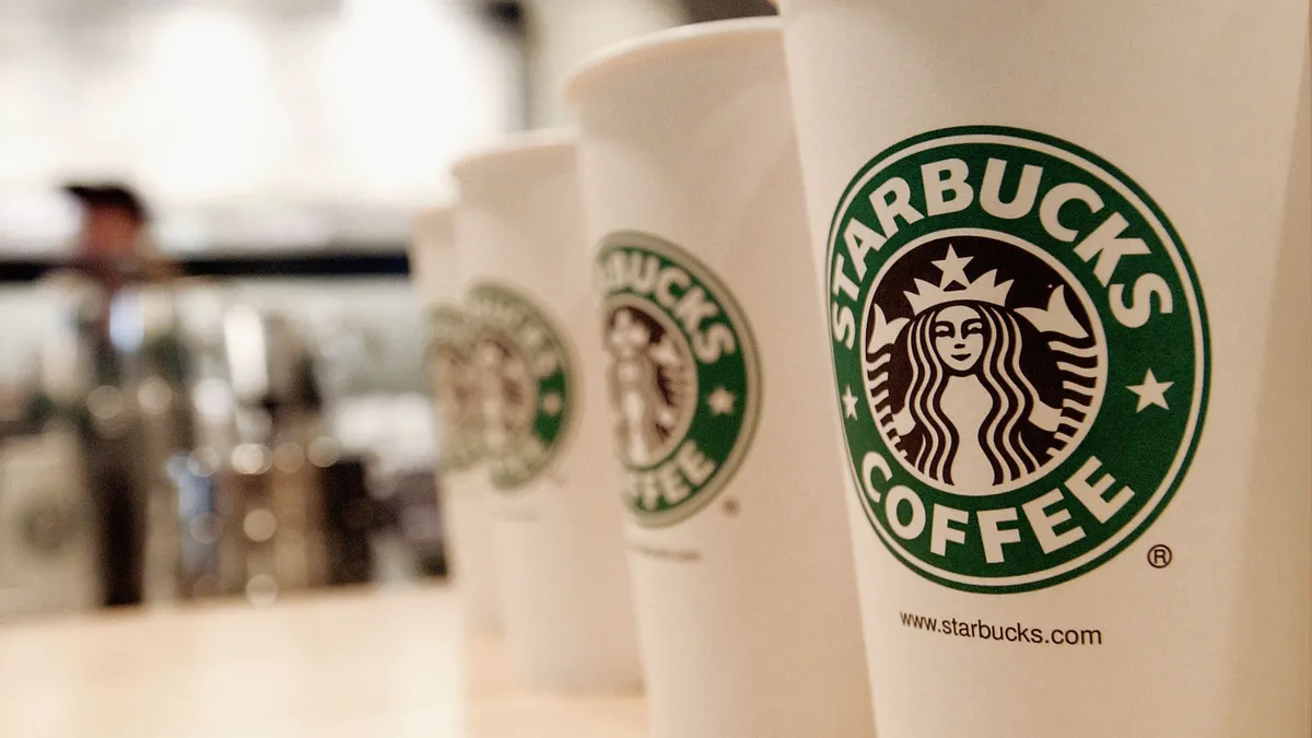 A closeup of beverage cups featuring the logo of Starbucks Coffee.