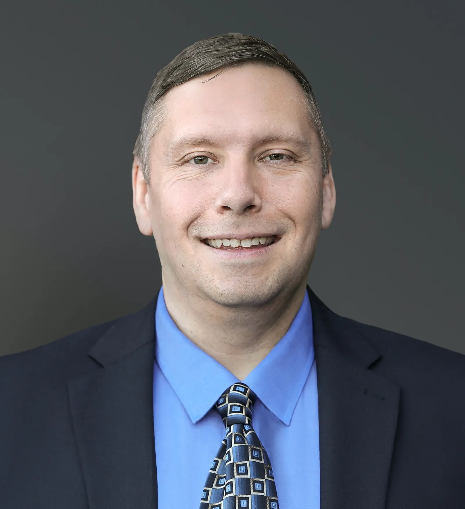 Headshot of a man in a suit and tie.