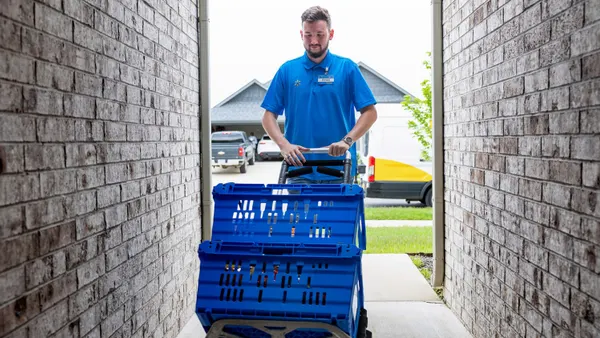 Walmart employee with two crates on a dolly outside of someone's home