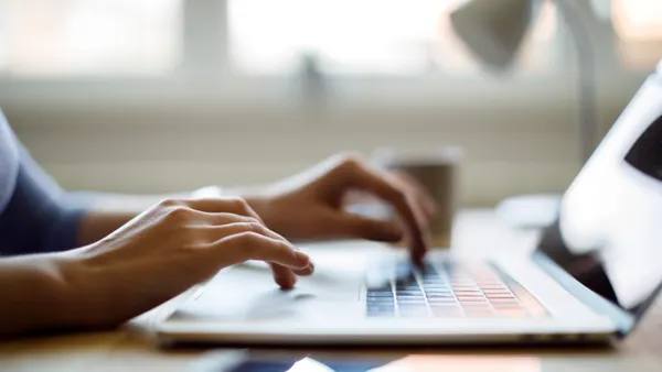 Close up of person's hands typing on a laptop