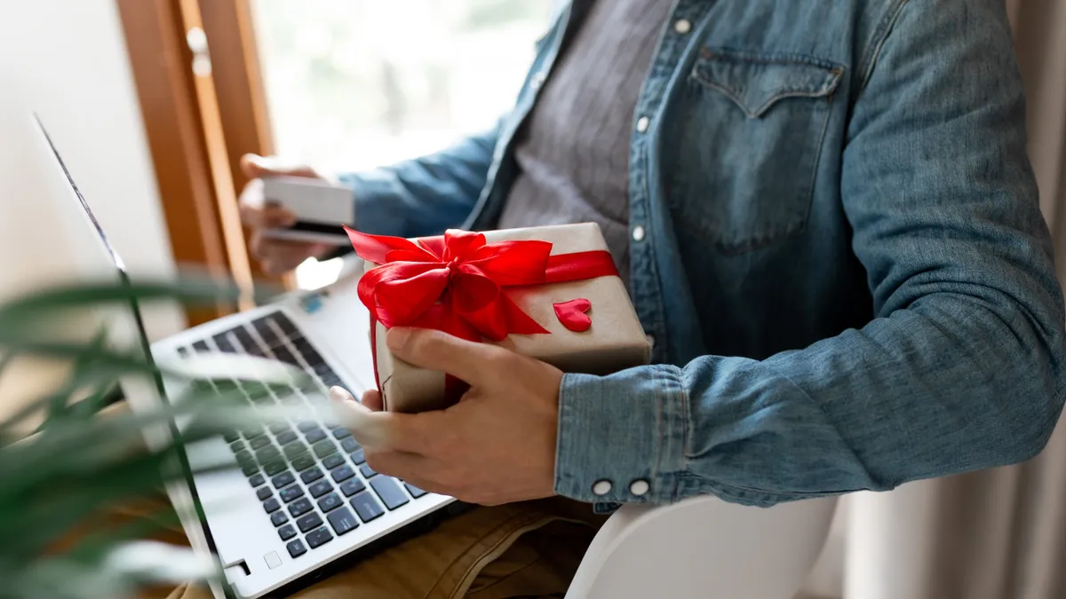 A person using a laptop and credit card to order gifts for Valentine's Day.