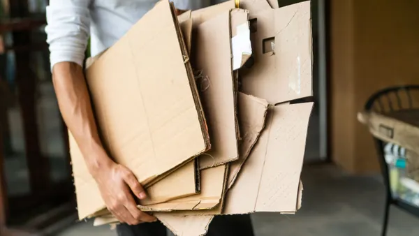 an arm holds flattened cardboard