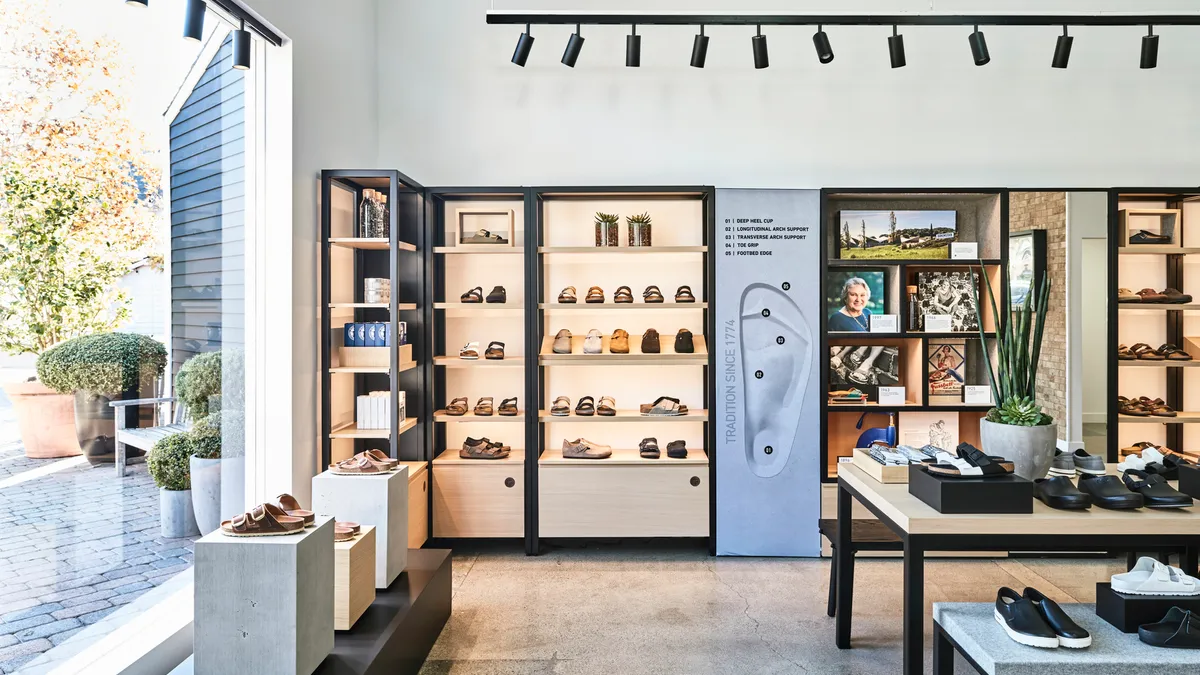 Inside shot of a Birkenstock store. Shoes are on pedestals in the window. Shoes are also on shelves and on tables on the right.