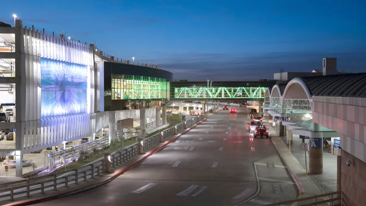 A shot at night of a car lane at the San Antonio International Airport with a bridge and the terminal.