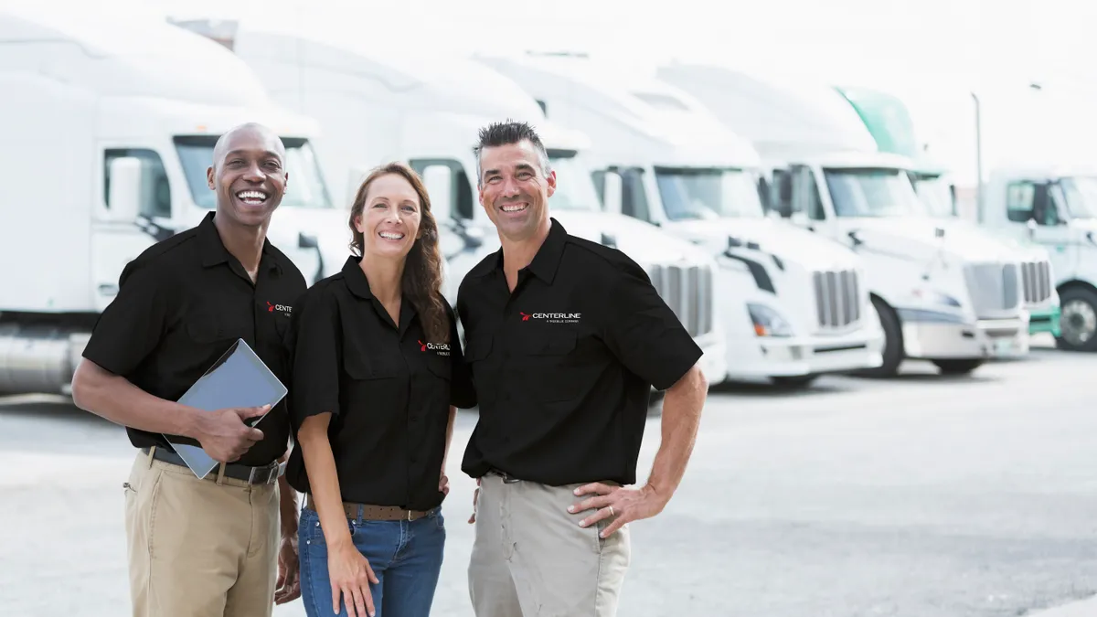 Three Centerline Drivers representatives stand in front of trucks.