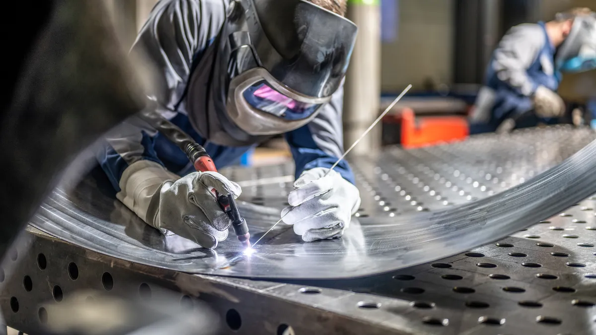 A person welds sheet metal.