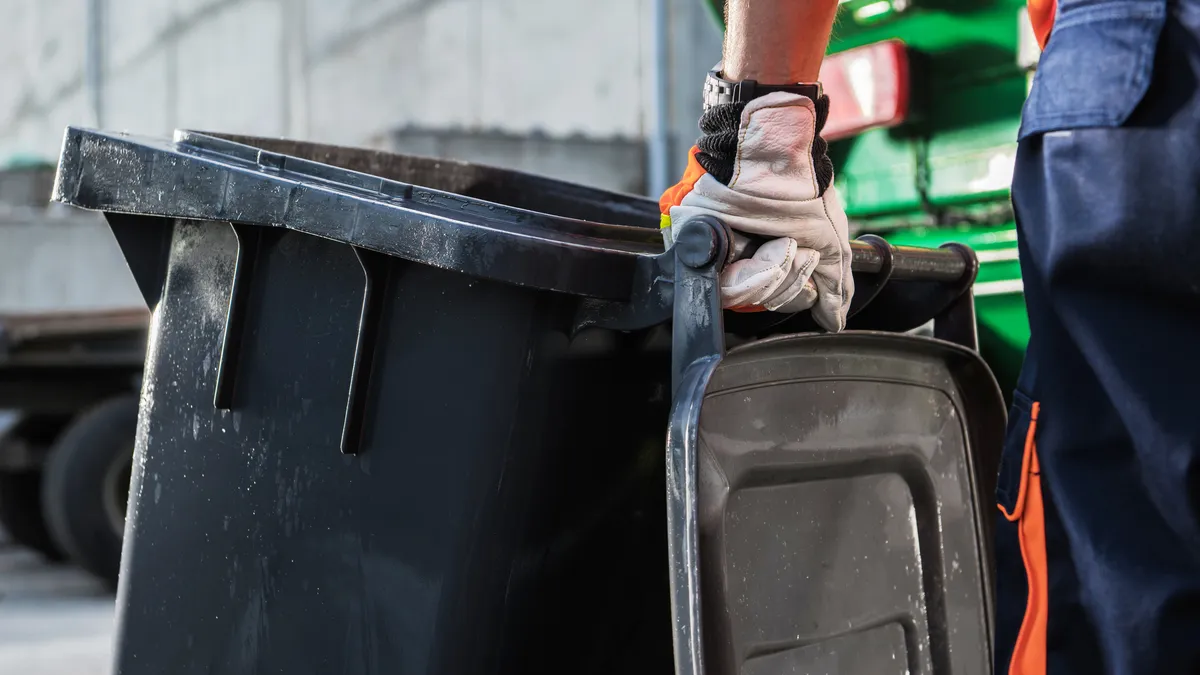 Gloved hand holding a garbage cart