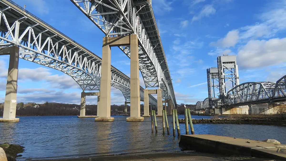 View from below of a twin silver bridges stretching across water.